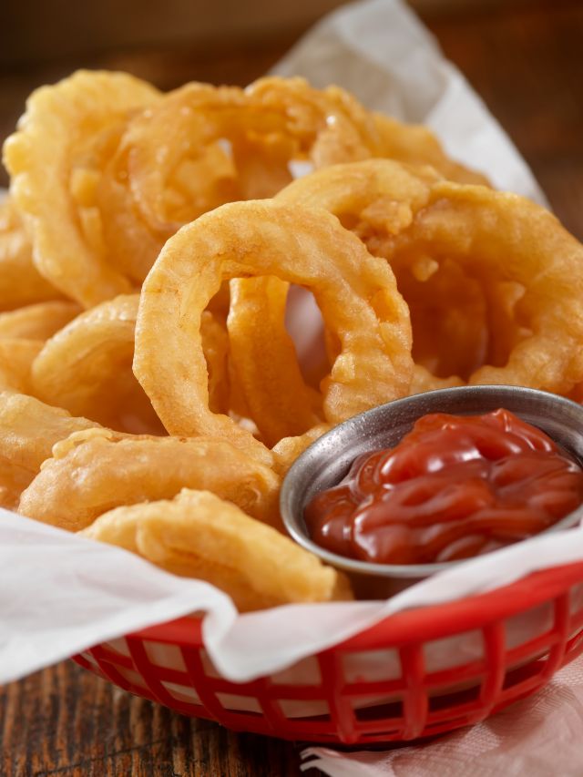 onion rings in a basket with ketchup
