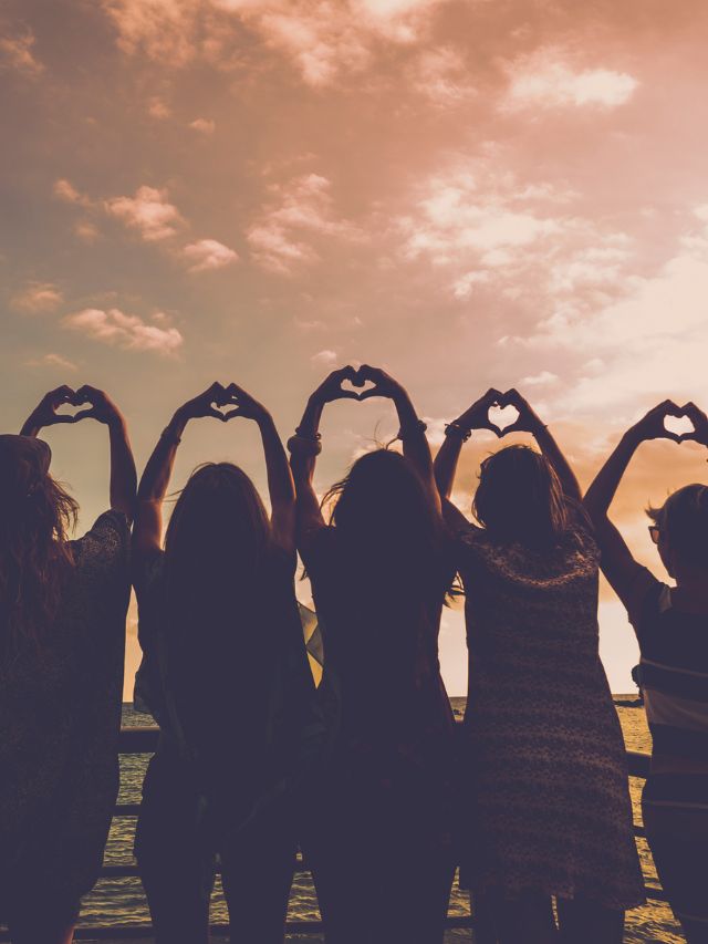 group of friends doing a heart hand gesture in the air