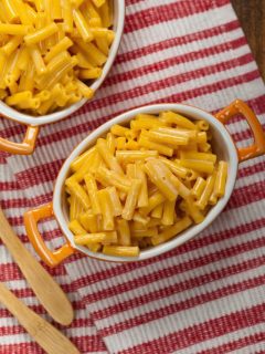 Two bowls of macaroni and cheese on a red and white striped cloth.