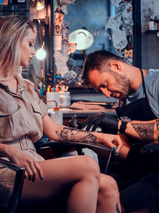 tattoo artist creating a new tattoo on woman's arm