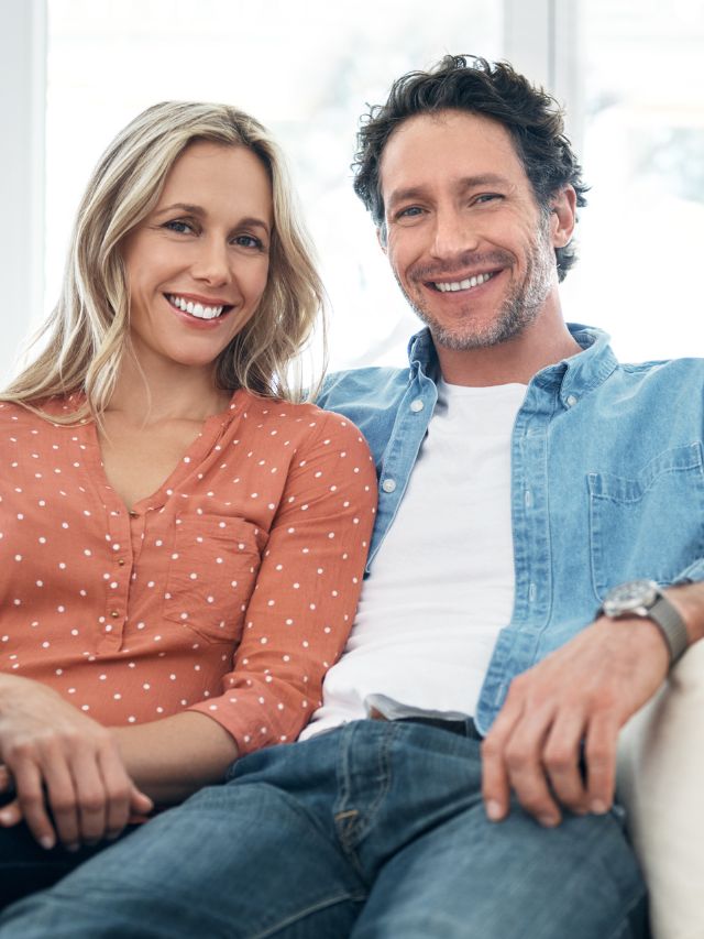 man and woman smiling on sofa