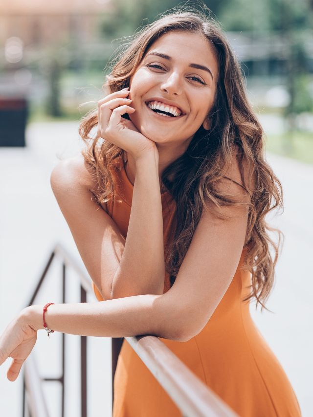 woman smiling and wearing orange dress