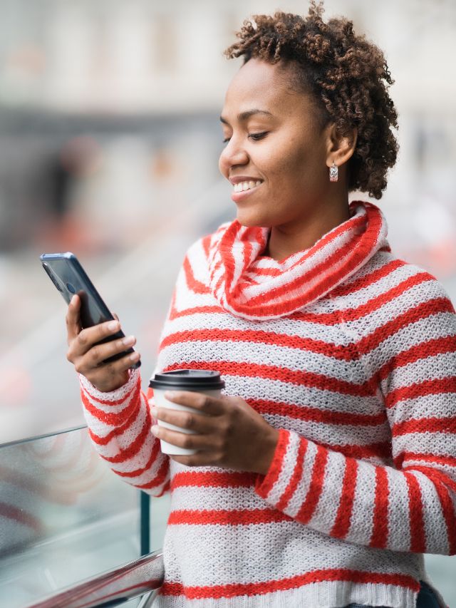 woman holding coffee and cell phone