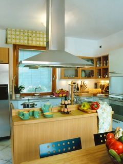 A kitchen with a wooden counter top and a top 10 kitchen island hoods.