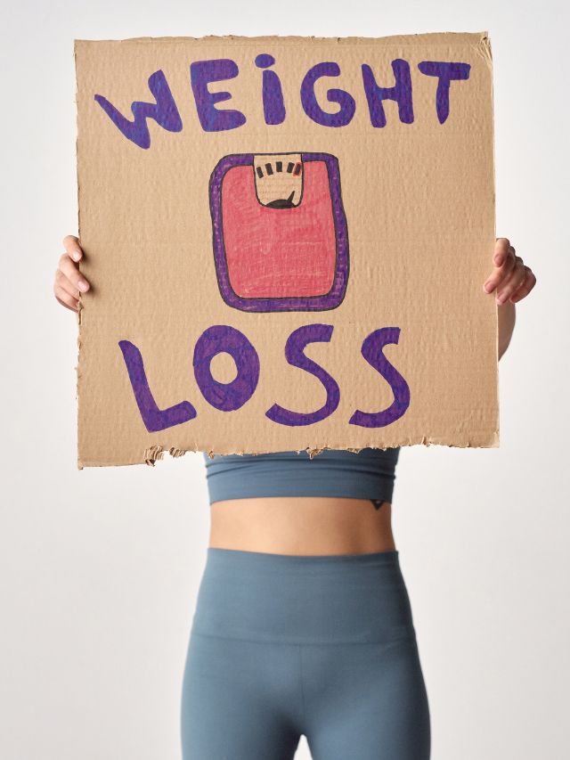 person holding cardboard with weight loss message on it 