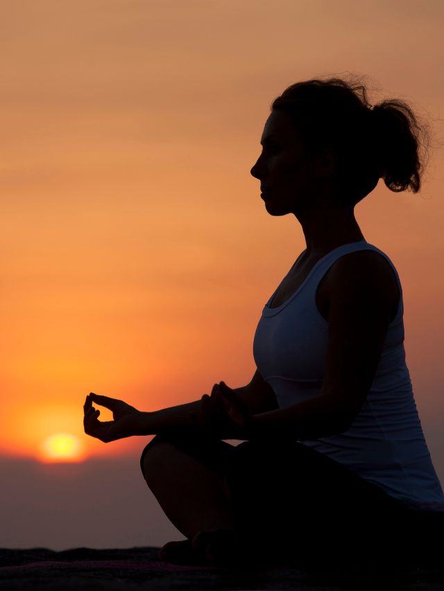 spiritual woman in lotus pose in front of sunset