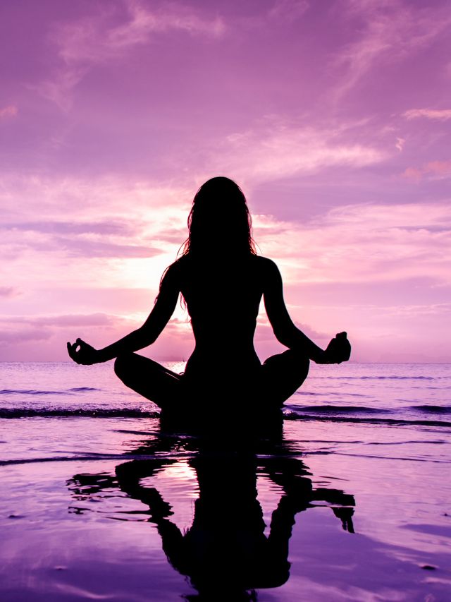 woman in lotus position sitting by the sea and meditating