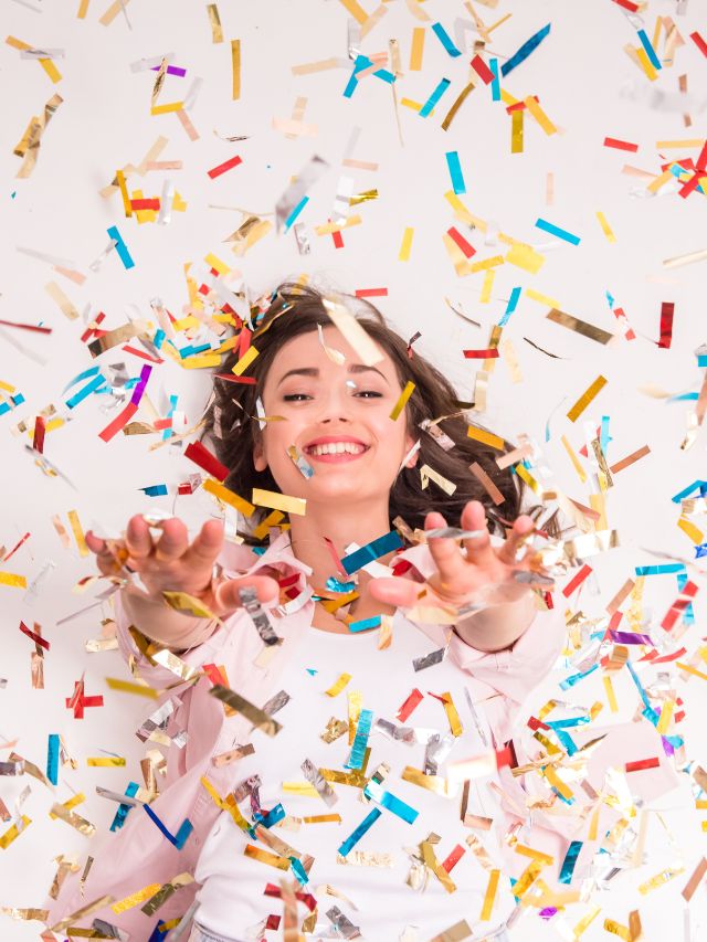 woman stretching out arms with confetti falling on her