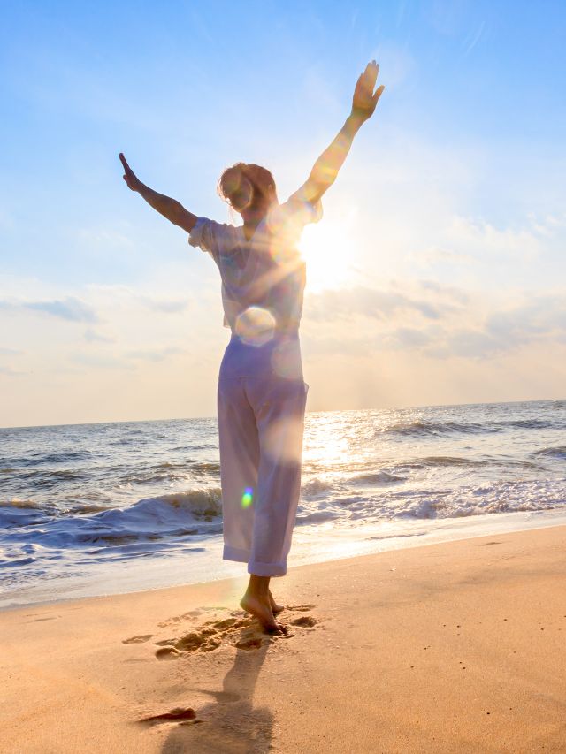 carefree woman dancing in the sun on the beach