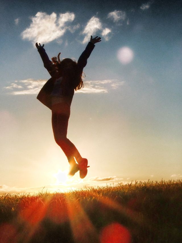girl jumping up in the air in front of sunset