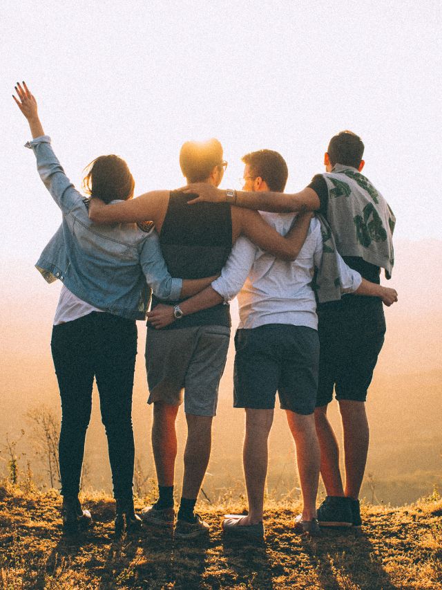 friends standing together at sunset on mountain