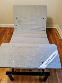 A Flexispot adjustable bed with a grey cover on top of it.