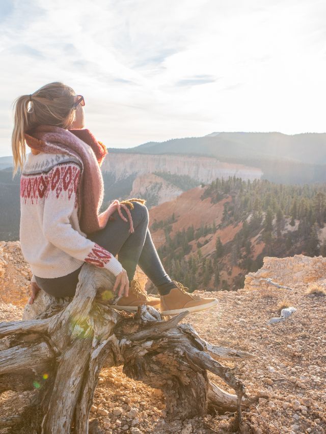 a woman sitting on a branch overlooking the Utah landscape
