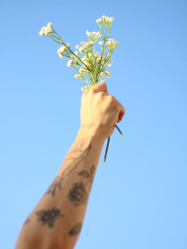 someone holding flowers with tattoos on arms