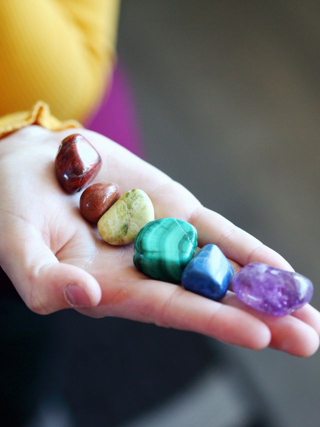 chakra crystals lined up on a hand