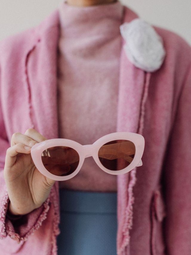 woman holding pink sunglasses
