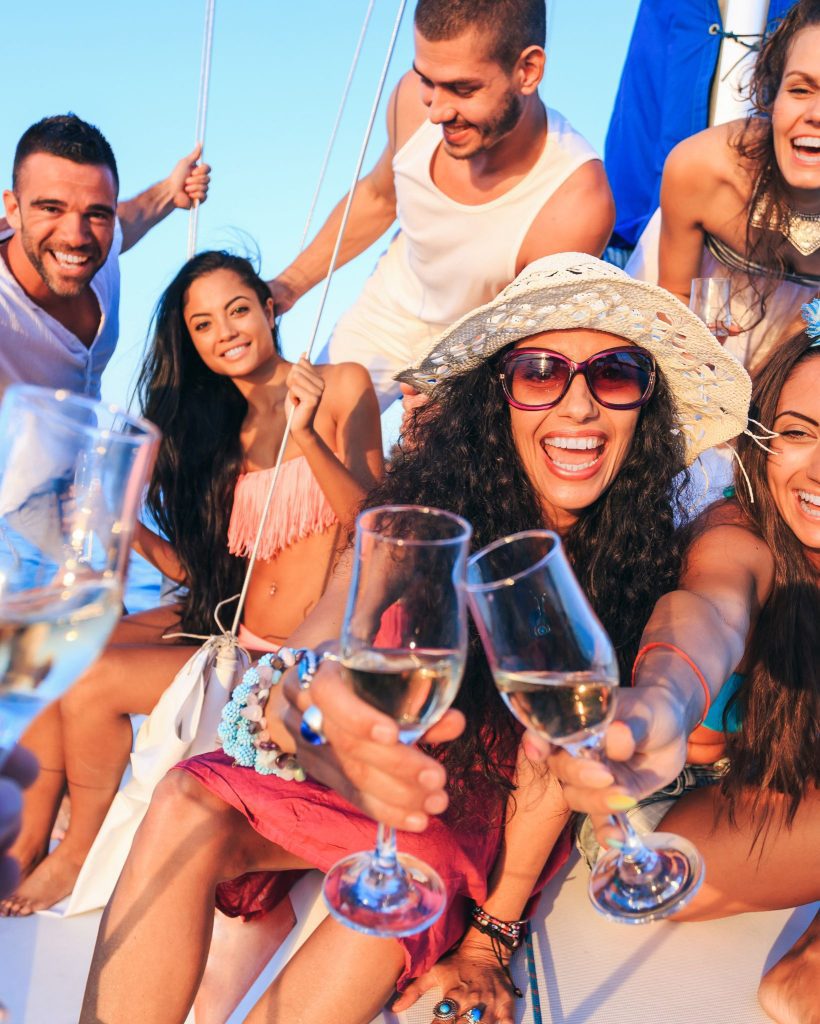 A group of friends on a boat enjoying wine while wearing comfortable summer yacht outfits.