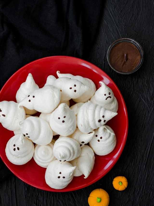 A plate of ghost cookies on a black background.