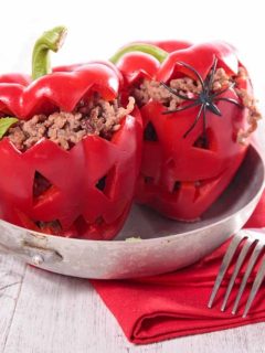 Two stuffed peppers with spiders and a fork on a plate.
