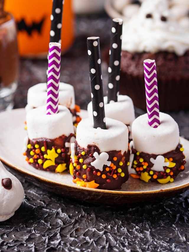 A plate with chocolate marshmallows and halloween decorations.