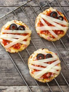 Three mummy pizzas on a cooling rack.