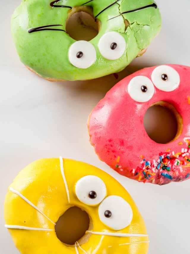 Three colorful donuts with eyes and sprinkles.