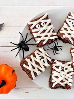Mummy brownies on a plate with spiders and pumpkins.