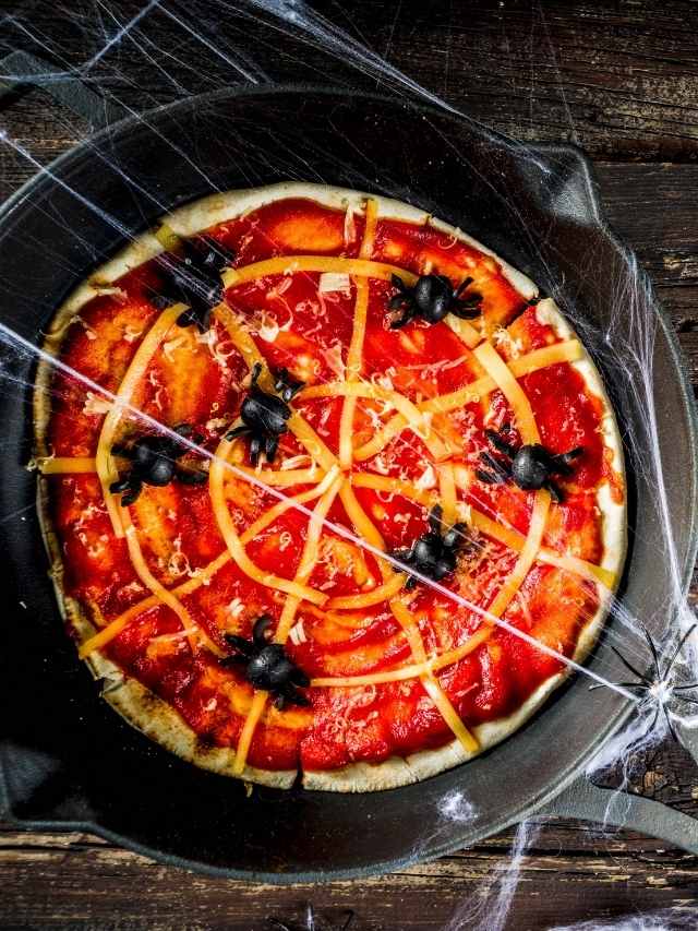 A pizza in a skillet with spider webs on it.