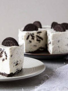 Oreo cheesecake on a plate with a slice taken out.