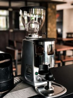 A coffee grinder sitting on a table in a restaurant.