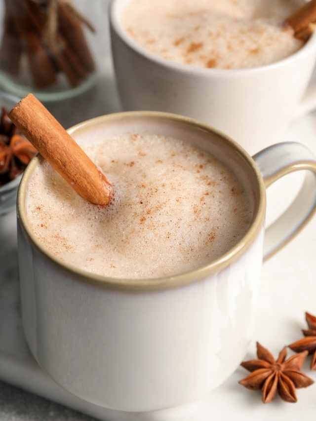 Two mugs of hot cocoa with cinnamon sticks and star anise.