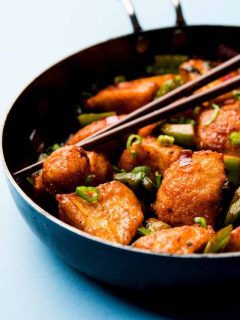 Chinese chicken stir fry in a wok with chopsticks.