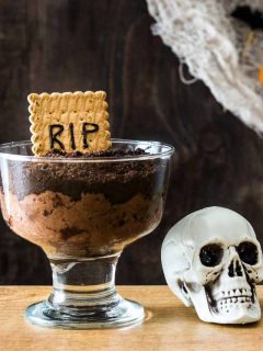 A halloween dessert in a glass bowl with a cookie and a skull.