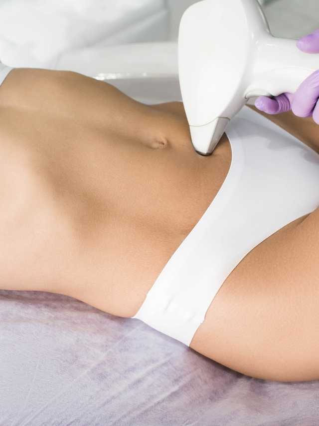 A woman is getting a laser treatment on her stomach.