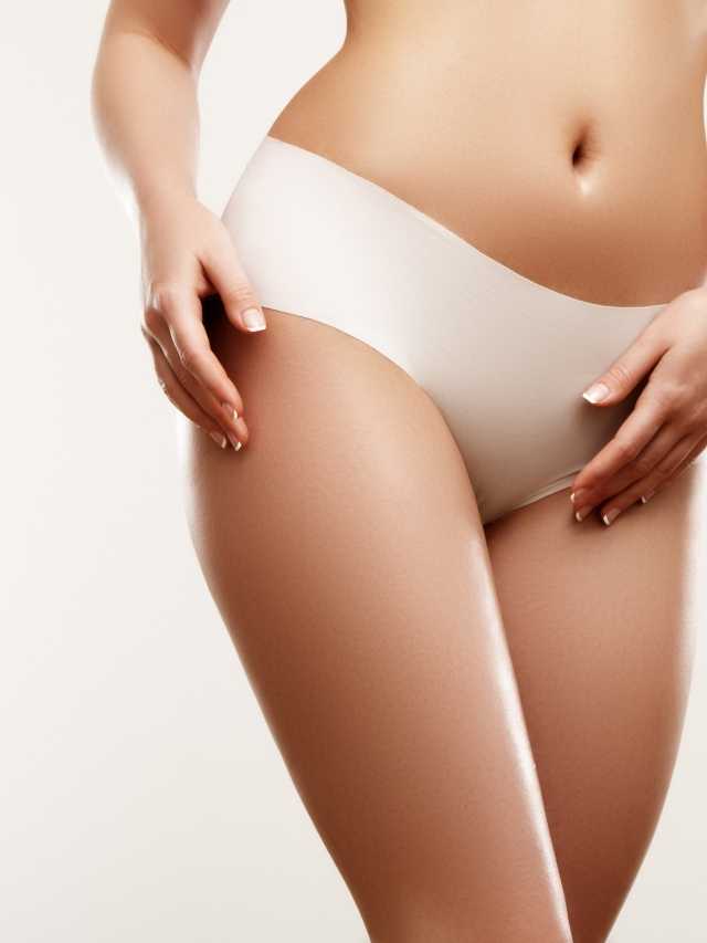 A woman in a white pantyhose posing in front of a white background.