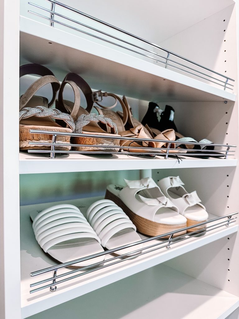 5 pairs of women's shoes sitting on a white shelf with silver bars