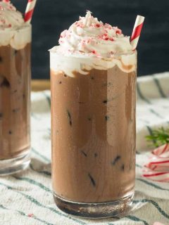 Two glasses of peppermint iced coffee with whipped cream and candy canes.