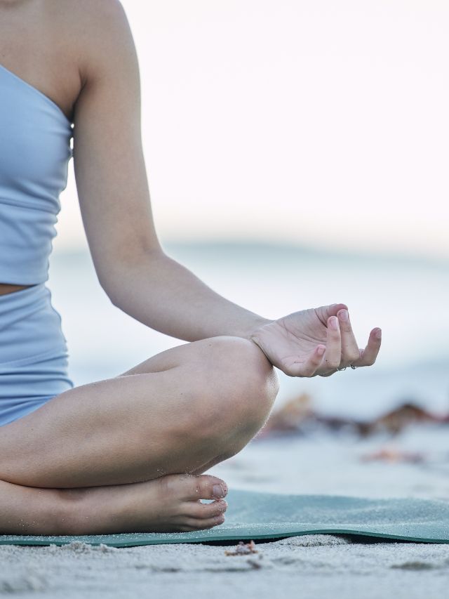 A woman is practicing meditation on a serene beach.