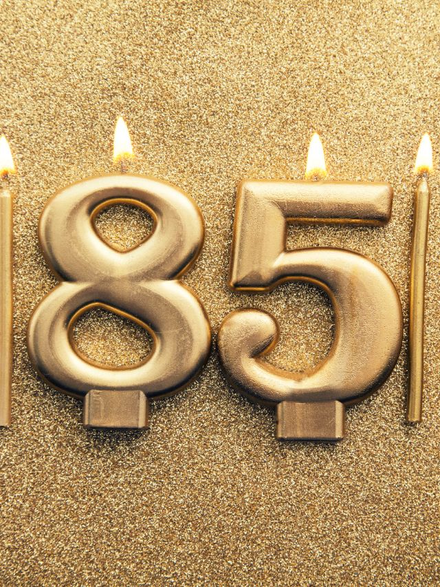 A golden number 85 with candles on a gold background representing the angelic meaning.