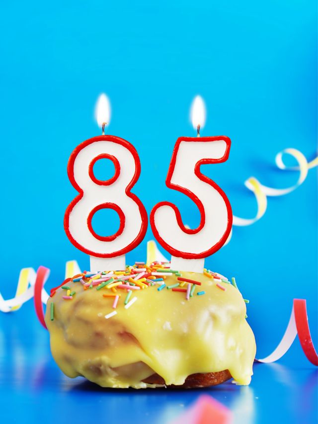 85th birthday cake with candles on a blue background.