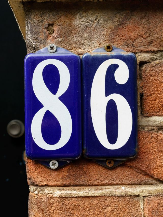 A blue and white house number on a brick wall.