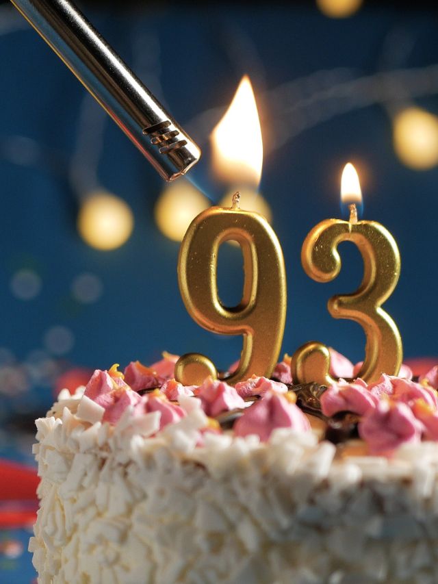 A cake with the number 99 lit up with a candle.