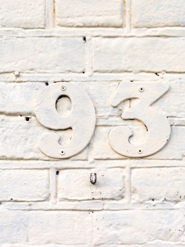 The number ninety-three is painted on a brick wall.