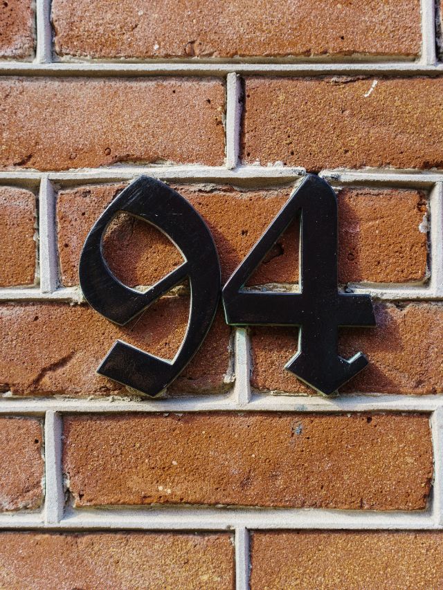 The symbolic angel number 94 displayed on a brick wall.