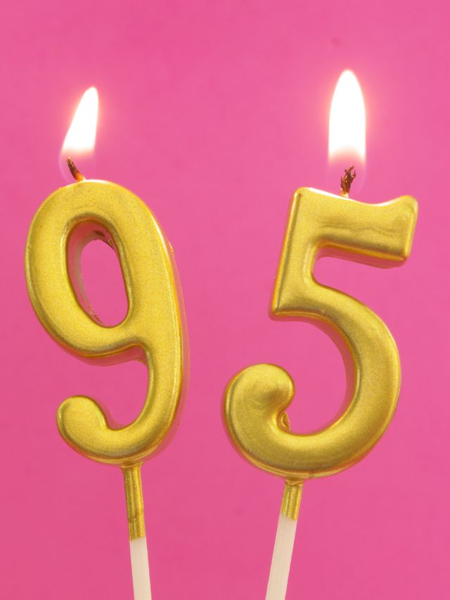 Two candles with the number 95 on them on a pink background.