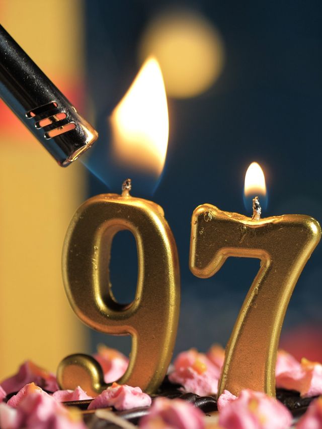 A candle is lit on a cake with the number 97.