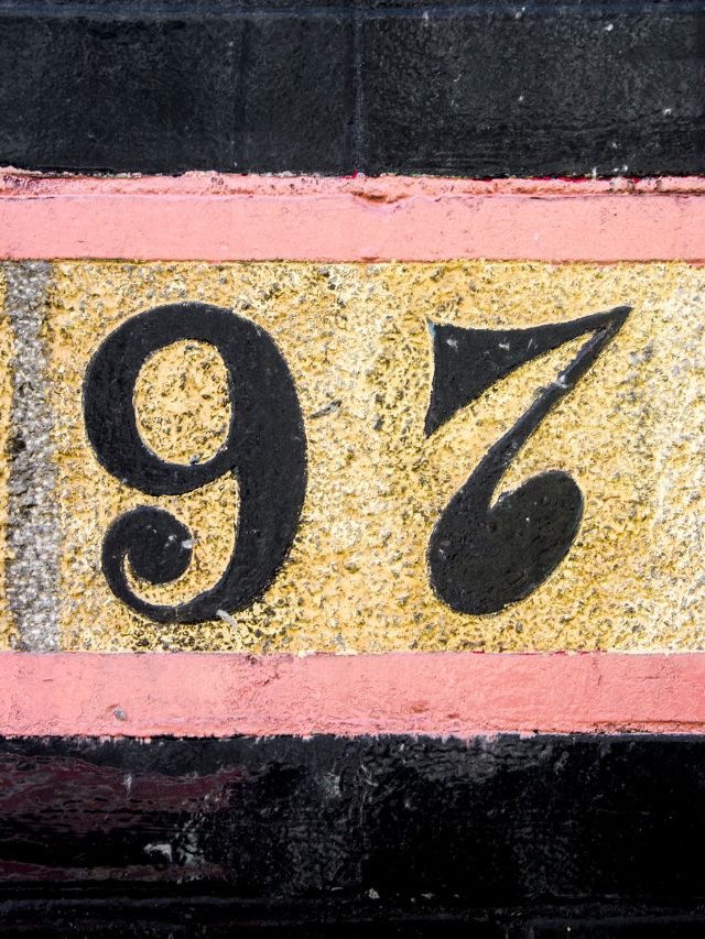 The number 97 painted on a brick wall.