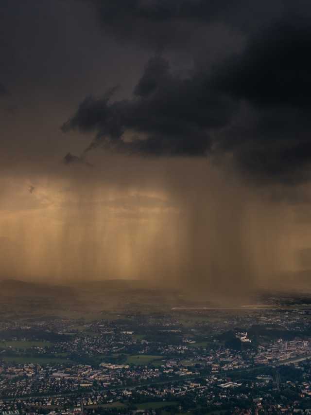 A rain storm over a city with a city in the background.