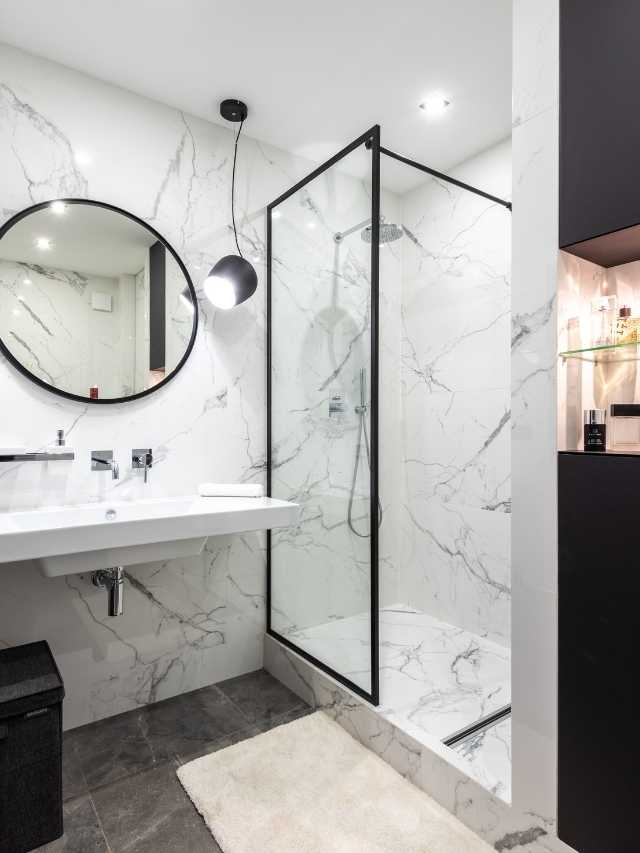 A black and white bathroom with marble walls.