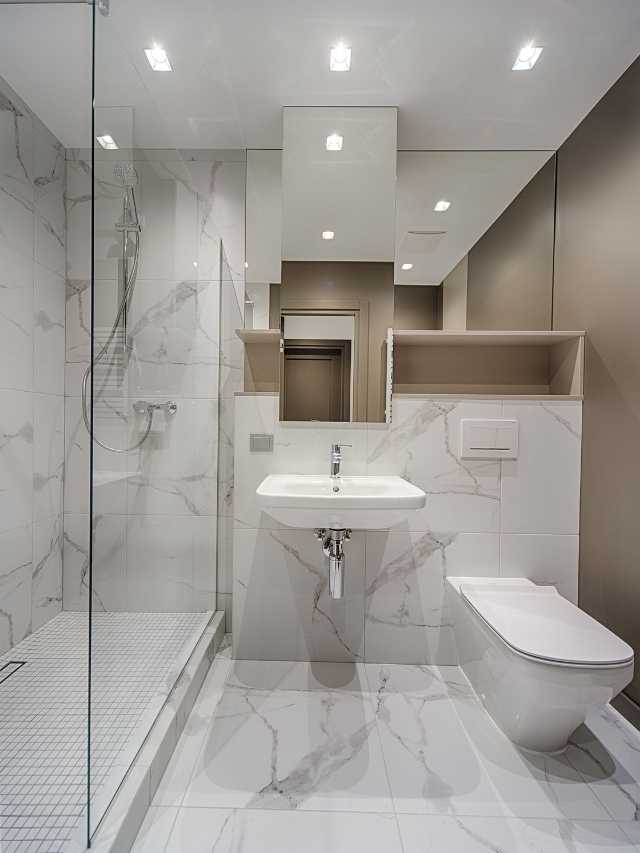 A white bathroom with marble floors and walls.